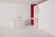 Ideal Standard Badearmatur mit Kreuzgriffen, verchromt, montiert an einem weißen Waschbecken, neben einer freistehenden Badewanne in modernem Badezimmerdesign mit roter Wand.